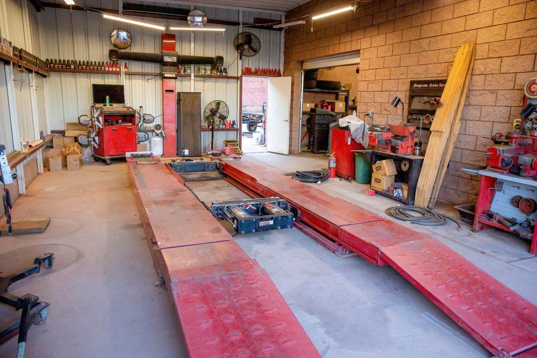 Auto repair garage with a car lift, red ramps, and tools in a workshop.