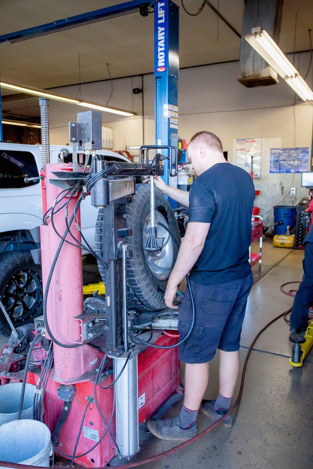 Mechanic working on a tire-changing machine in an auto repair shop