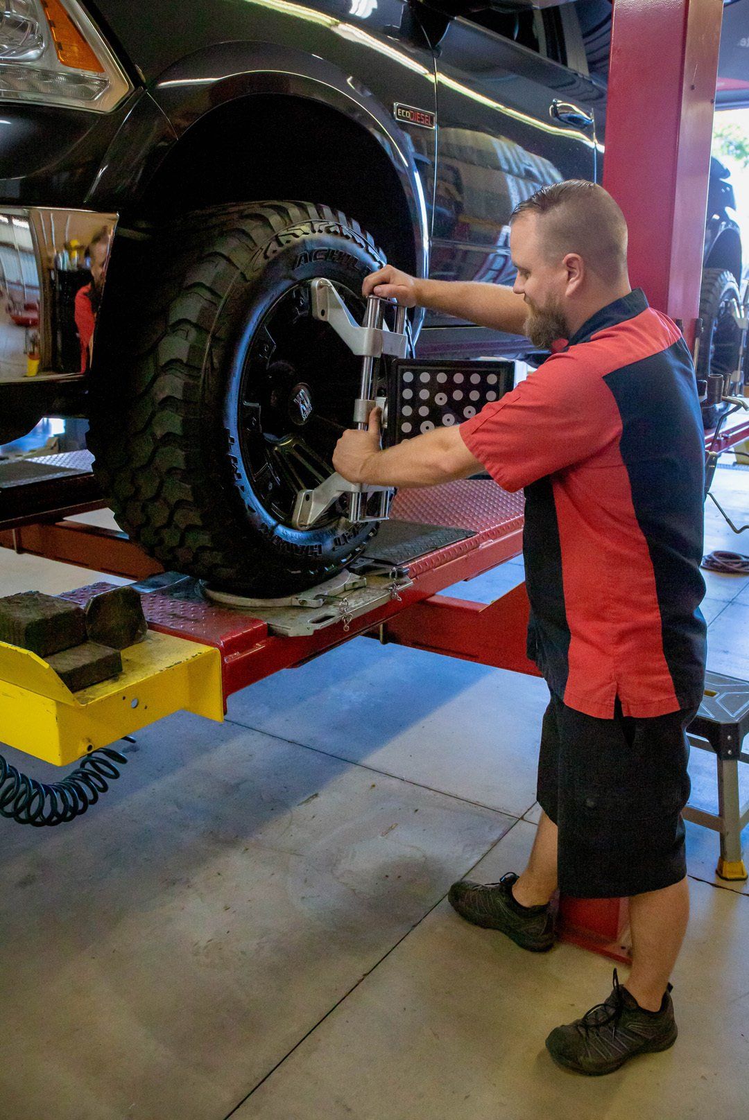 Mechanic tightening a truck wheel on a lift in an auto shop