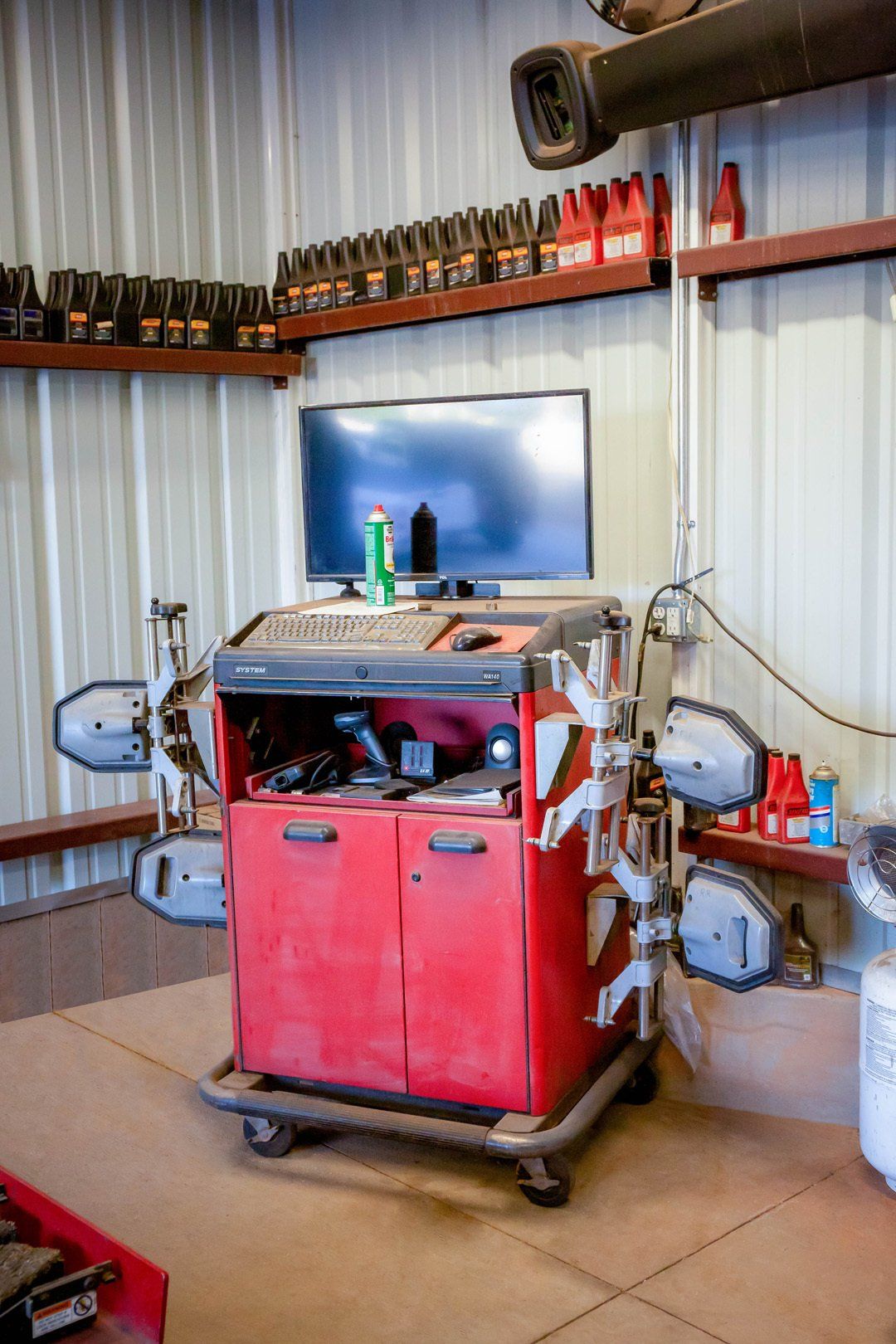 Red wheeled industrial machine in a metal workshop with tools and shelves in the background