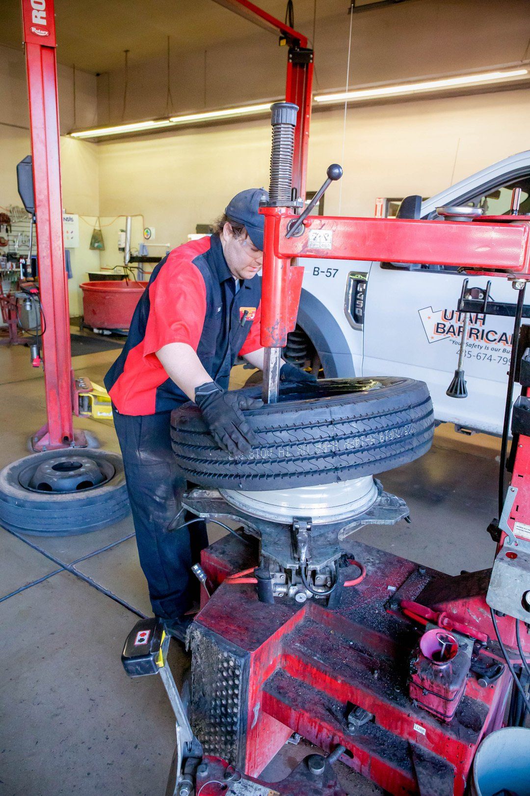 Mechanic using a tire-changing machine on a large tire in an auto shop