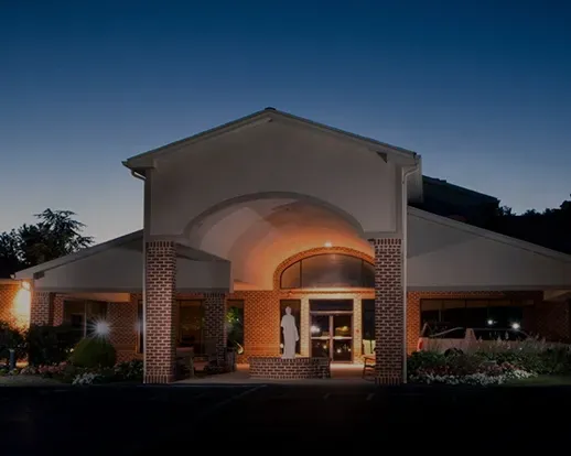 Front entrance of a building at dusk, warmly lit under a peaked archway