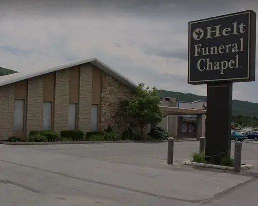 Helt Funeral Chapel building with roadside sign under a cloudy sky