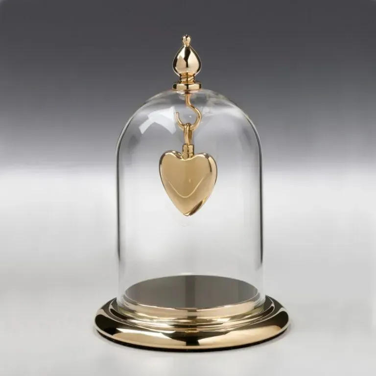 Gold heart pendant under a clear glass dome on a gold base