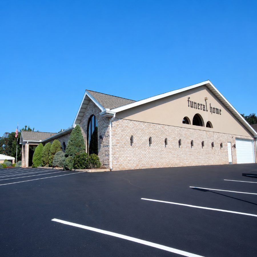 Exterior of brick funeral home with landscaped grounds and parking lot blue sky. Dallastown, PA Funeral Home and Cremations