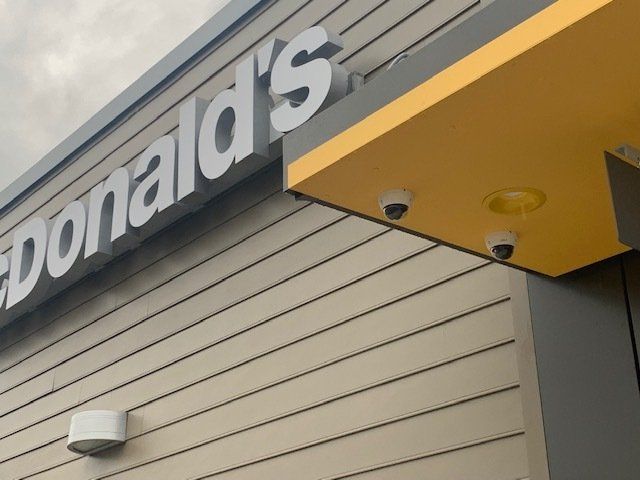 McDonald's exterior with a large sign, security cameras, and a yellow overhang.