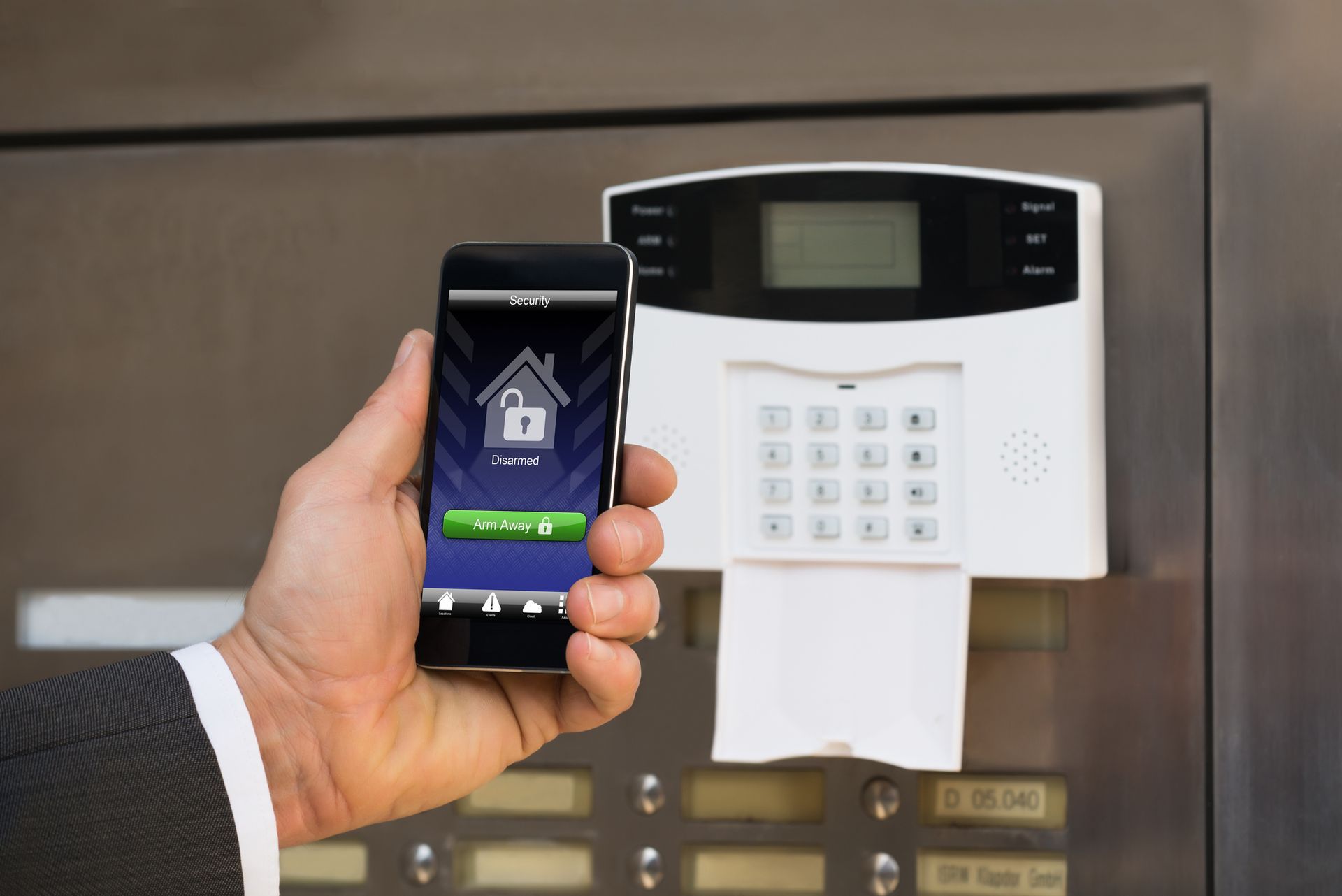 Hand in a suit holds a smartphone as it unlocks the security door in a building. Hand in a suit holds a smartphone as it unlocks the security door in a building.