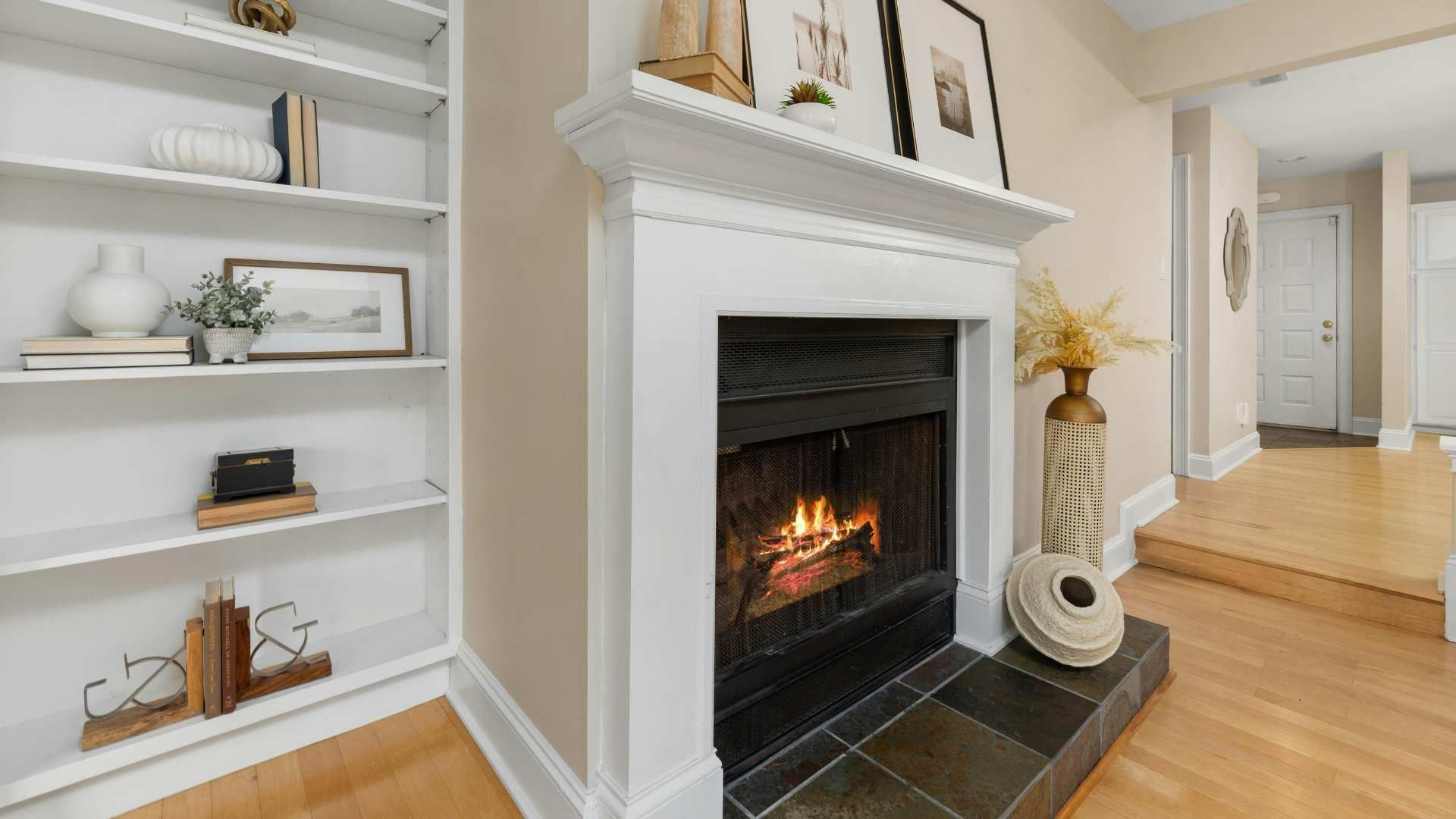 Bright living room with white built-in shelves and a white fireplace on hardwood floors