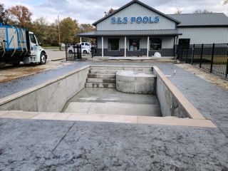 A large swimming pool is being built in front of a building.