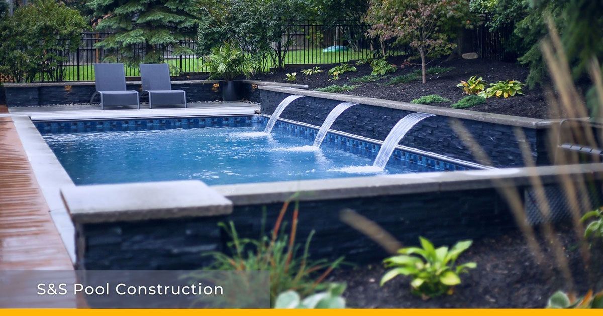 A large swimming pool with a waterfall in the backyard