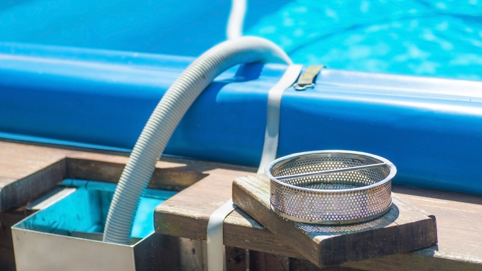 A hose is attached to the side of a swimming pool.