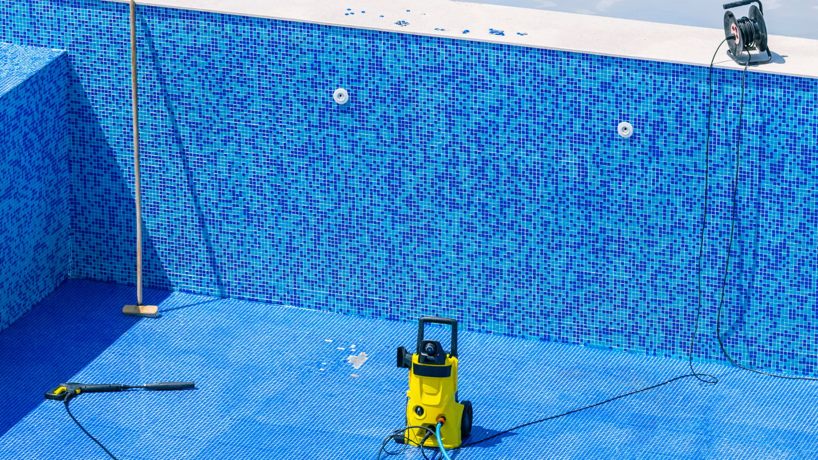 A yellow vacuum cleaner is sitting in the middle of an empty swimming pool.
