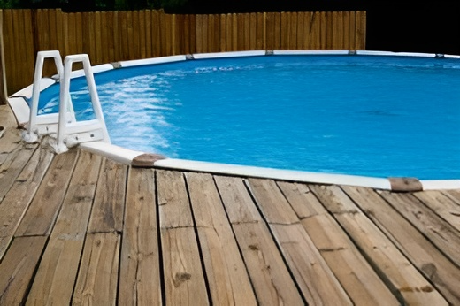 A swimming pool with a wooden deck surrounding it
