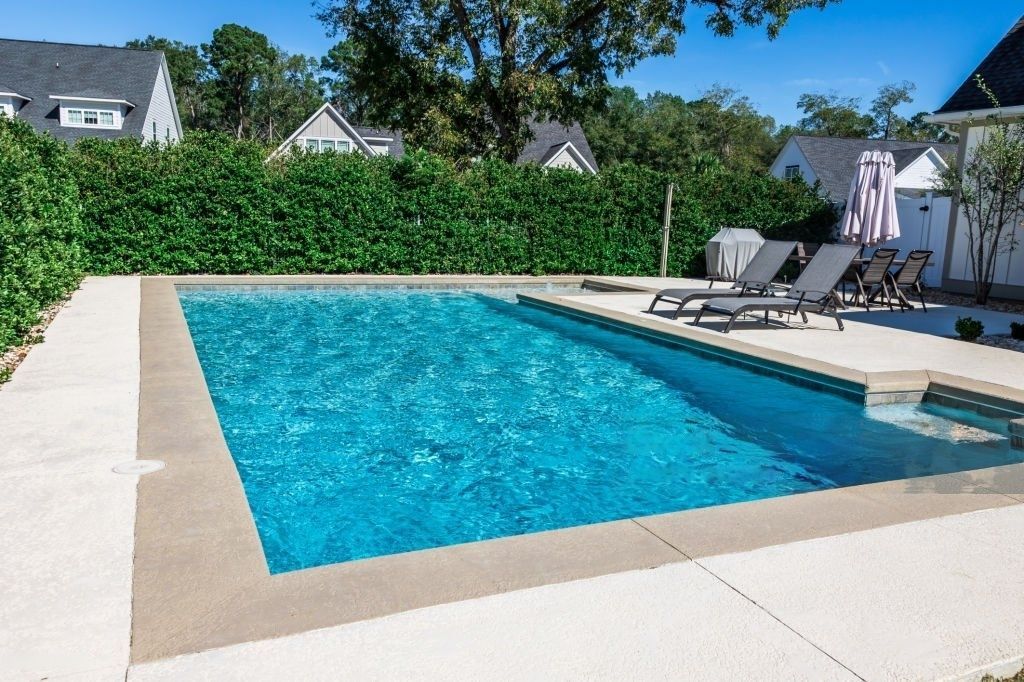 A large swimming pool surrounded by chairs and a fence