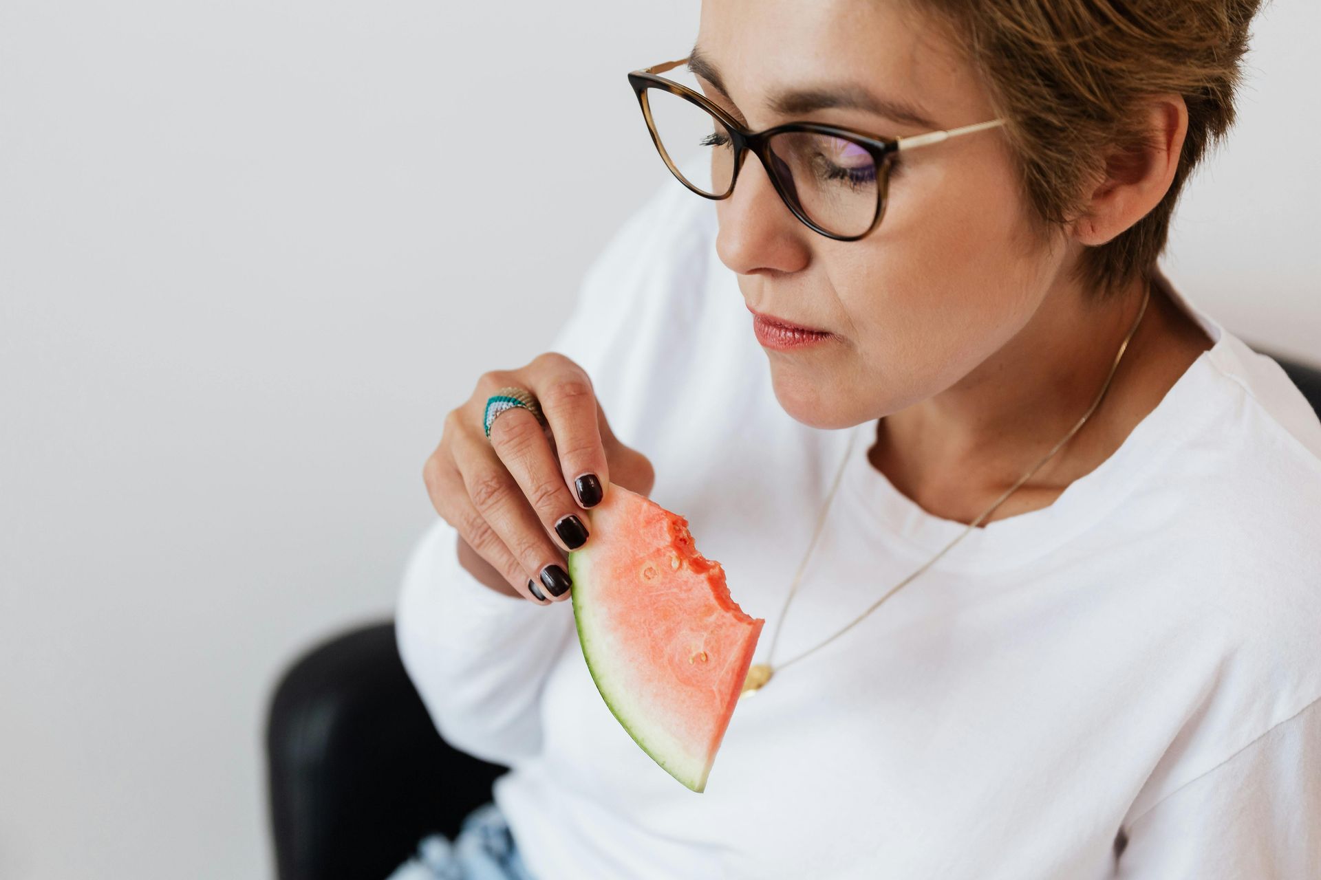 A Person Wearing Glasses and a White Shirt Holds a Slice of Watermelon — Cathie Barnes Holistic Wellness in Yeppoon, QLD