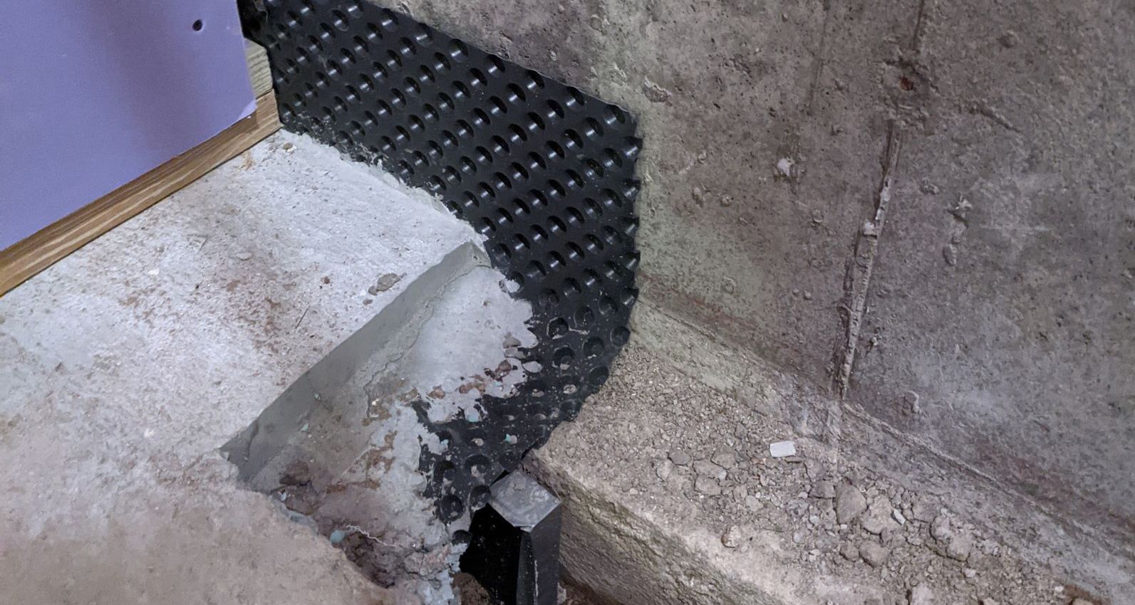A person is working on a concrete wall with a trowel.