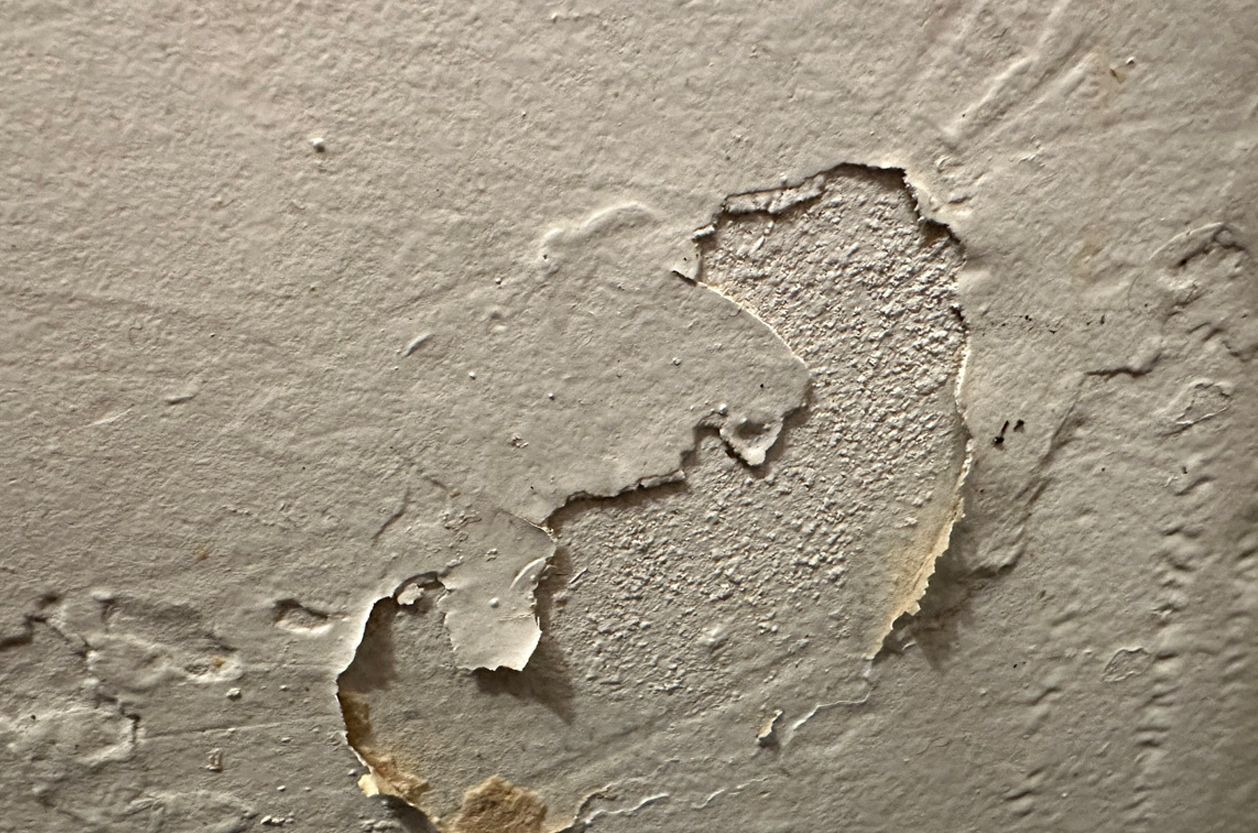 a close up of a wall with peeling paint and a hole in it