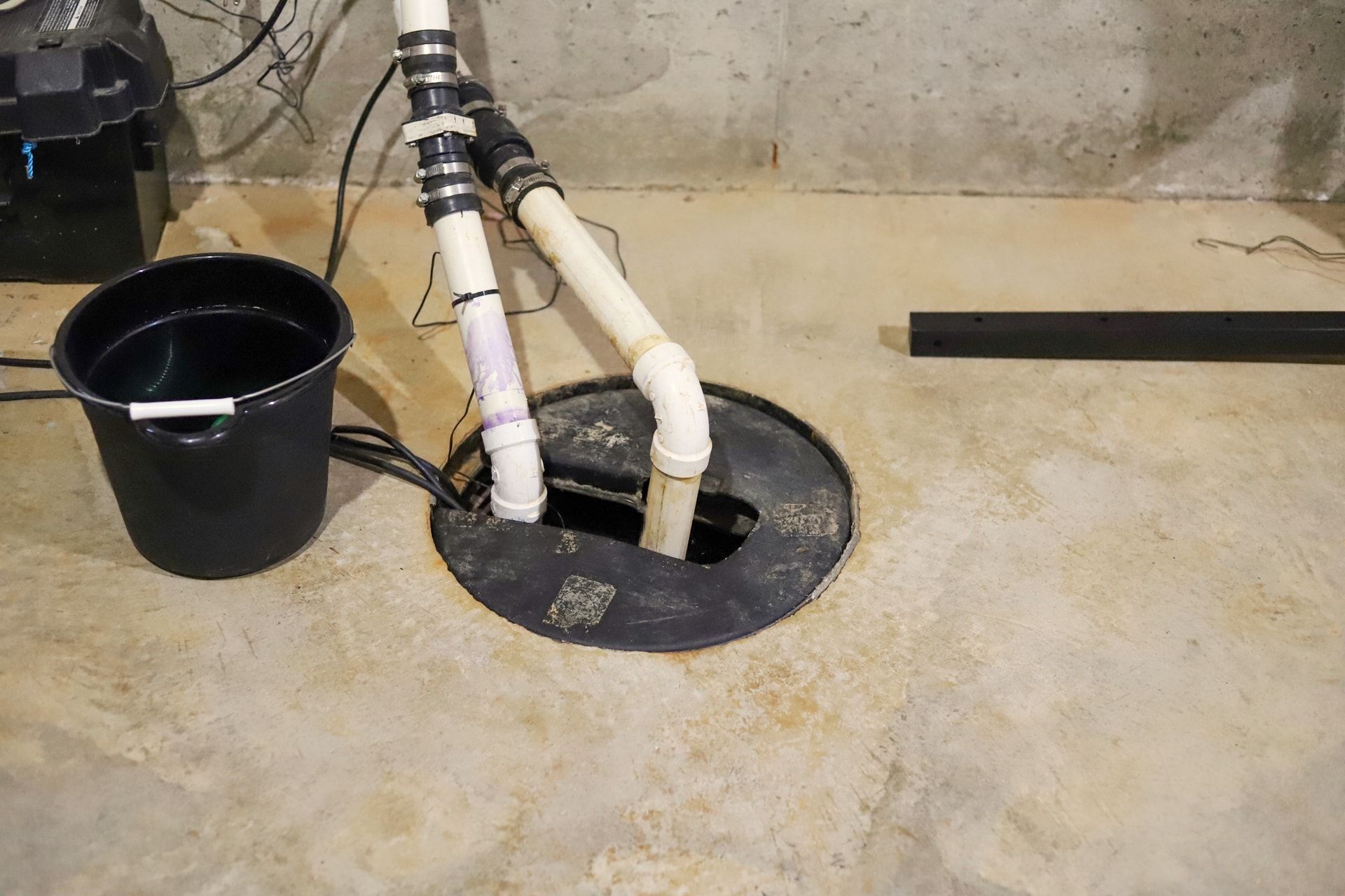a bucket of water is sitting next to a sump pump in a basement .