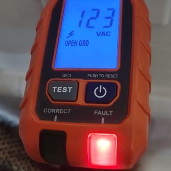 An orange electrical outlet tester displays