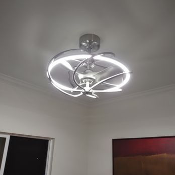 Ceiling fan with integrated LED lights, silver finish, in a room with white walls and artwork.