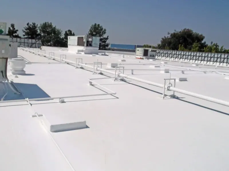 White rooftop with HVAC units, vents, and piping under a clear blue sky