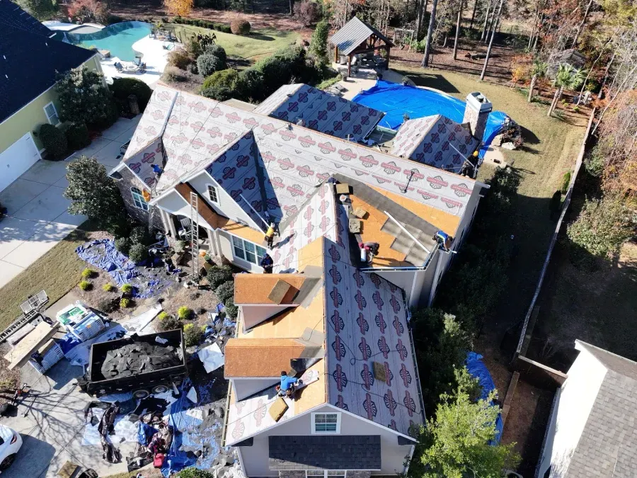 Damaged house roof under repair with debris and exposed framing, viewed from above