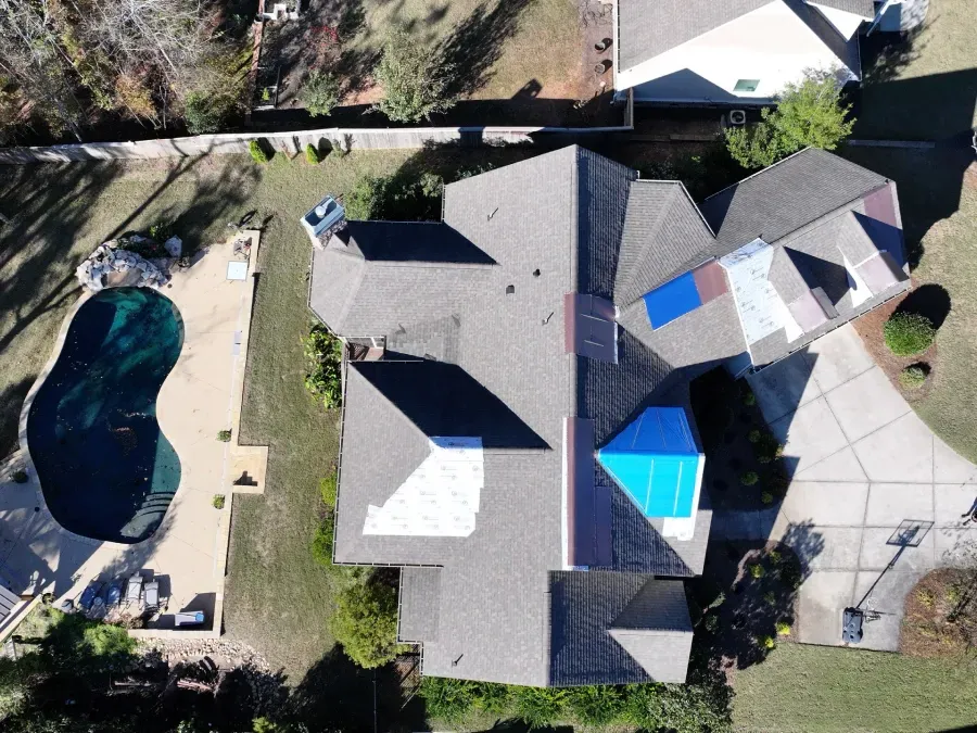 Aerial view of a house with a backyard pool, patio, and driveway.