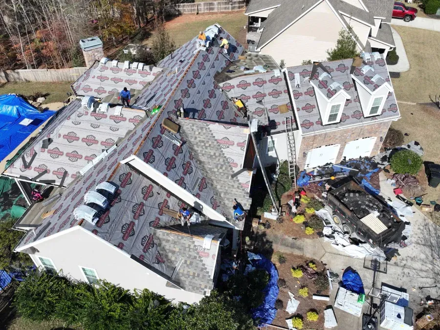 Aerial view of storm-damaged houses with torn roofs and scattered debris after severe weather