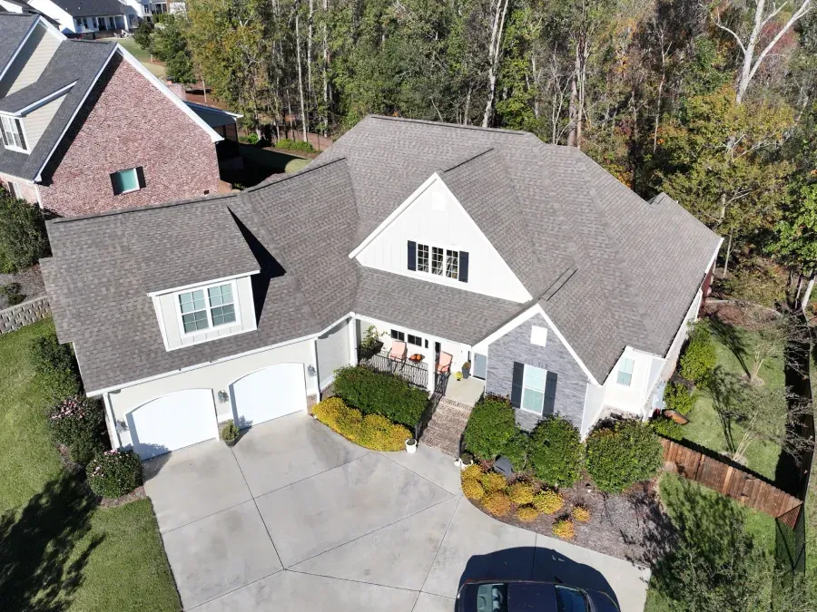 Aerial view of a white suburban house with a two-car garage and landscaped front yard.