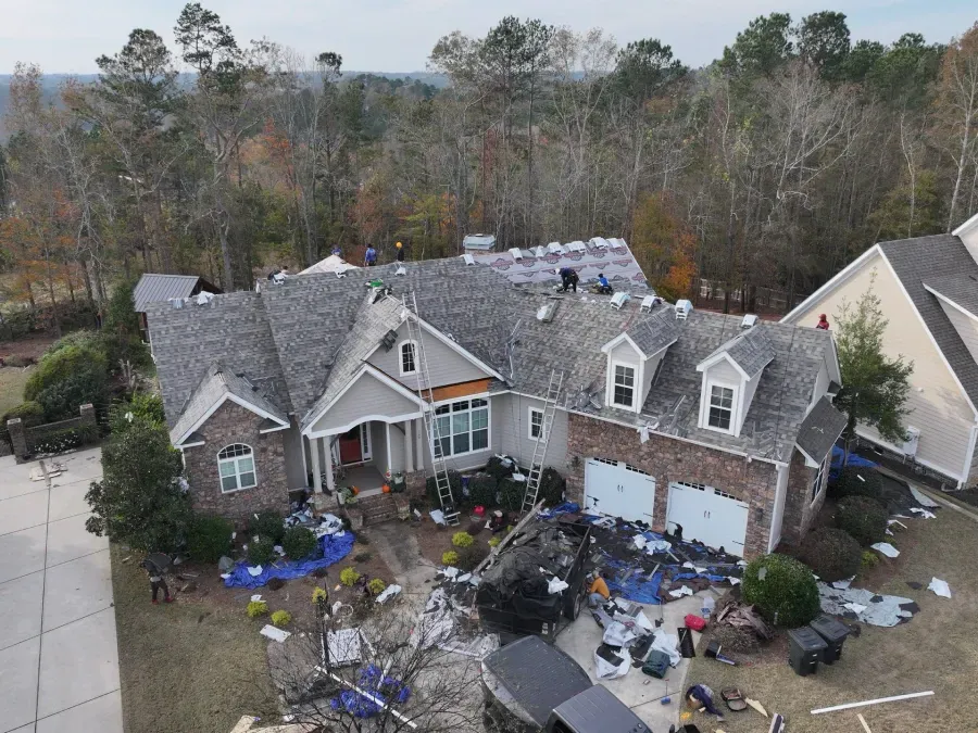 Aerial view of a suburban house with storm damage and debris scattered across the yard.