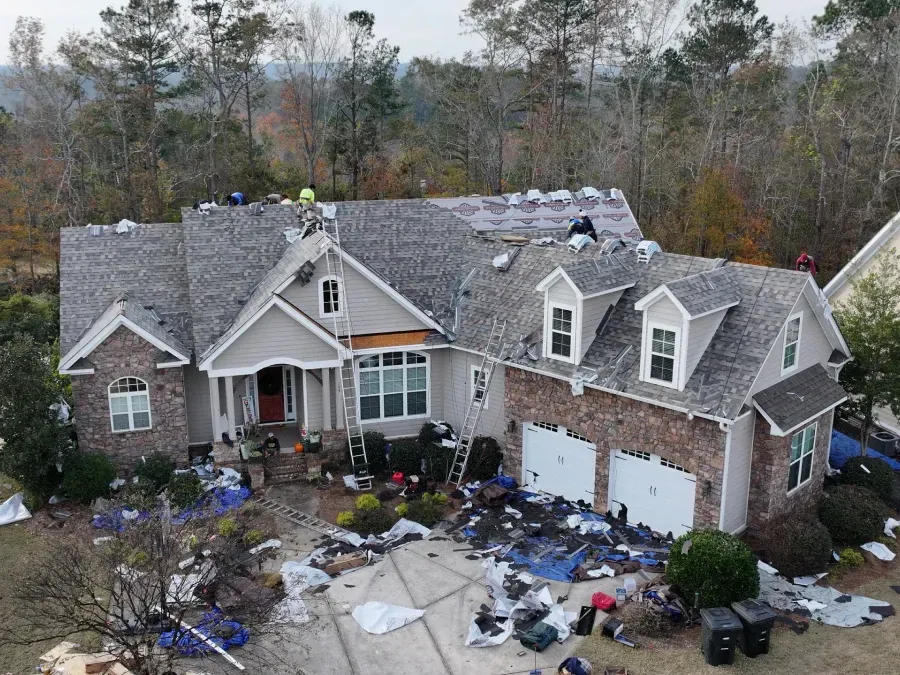 A damaged house with a caved-in roof and debris scattered across the front yard.