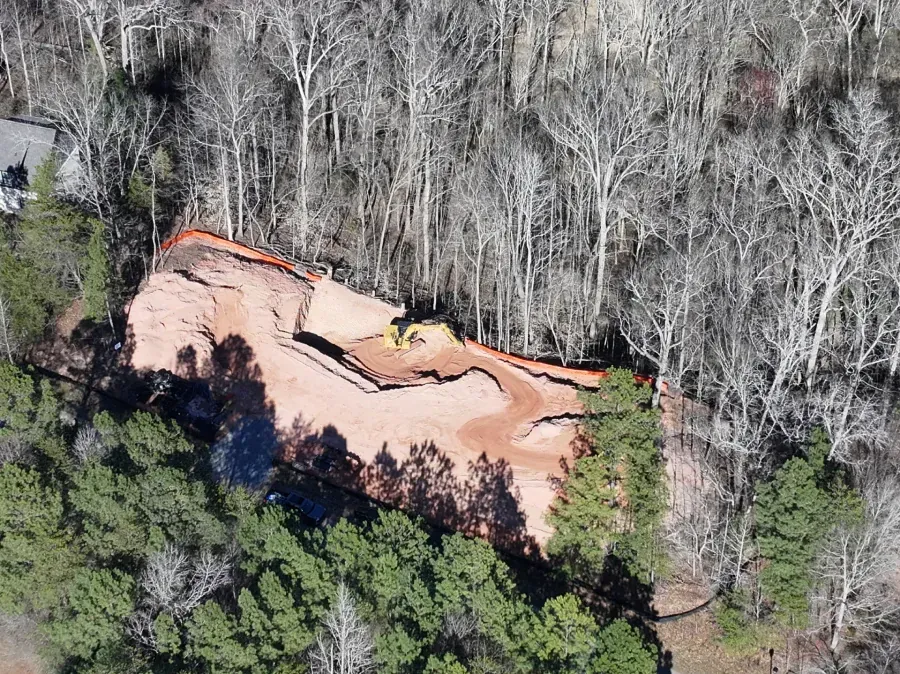 Aerial view of a pink rock quarry surrounded by dense trees and forest