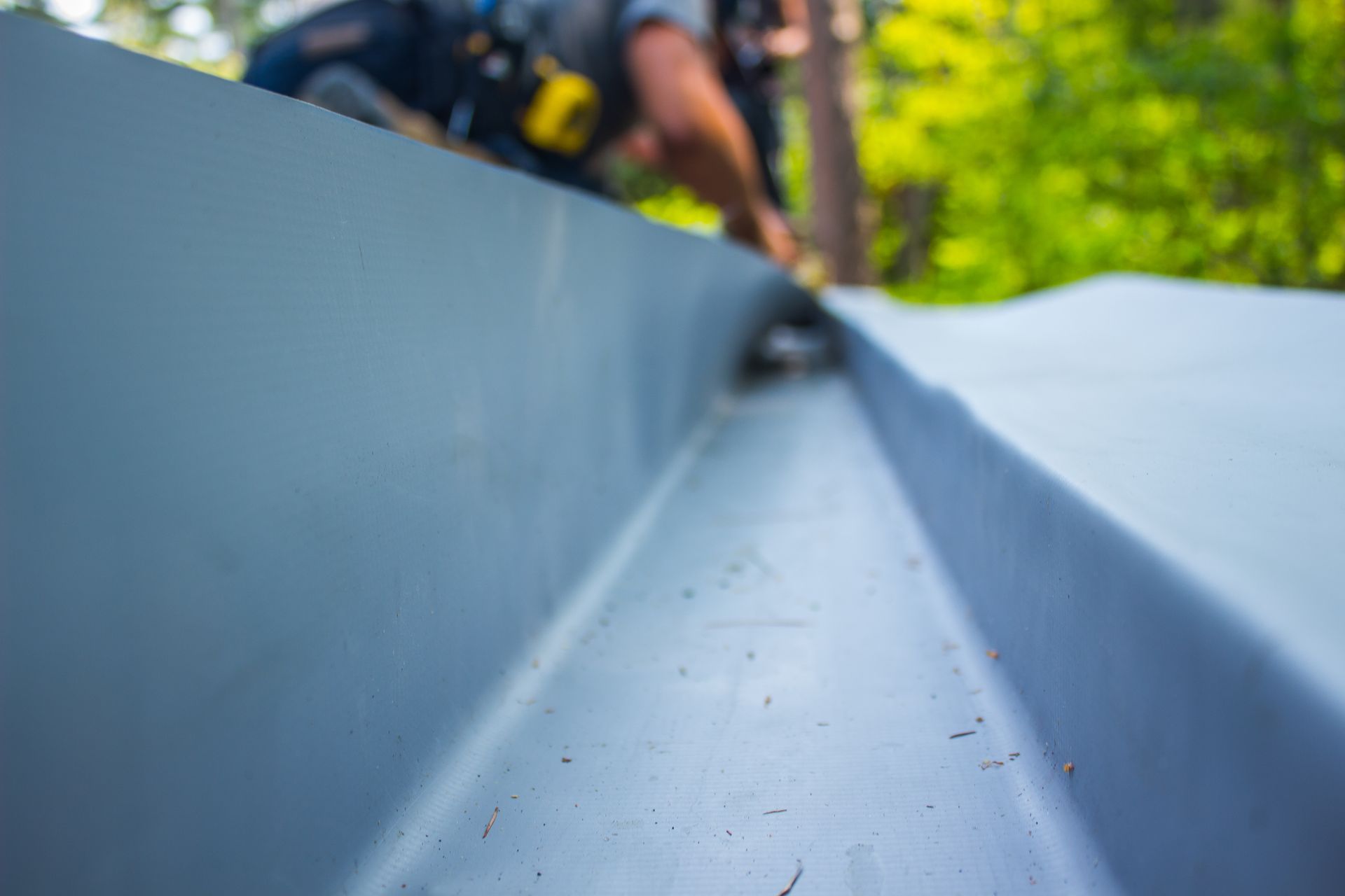 Workers installing a blue metal roof panel outdoors, close-up with blurred background