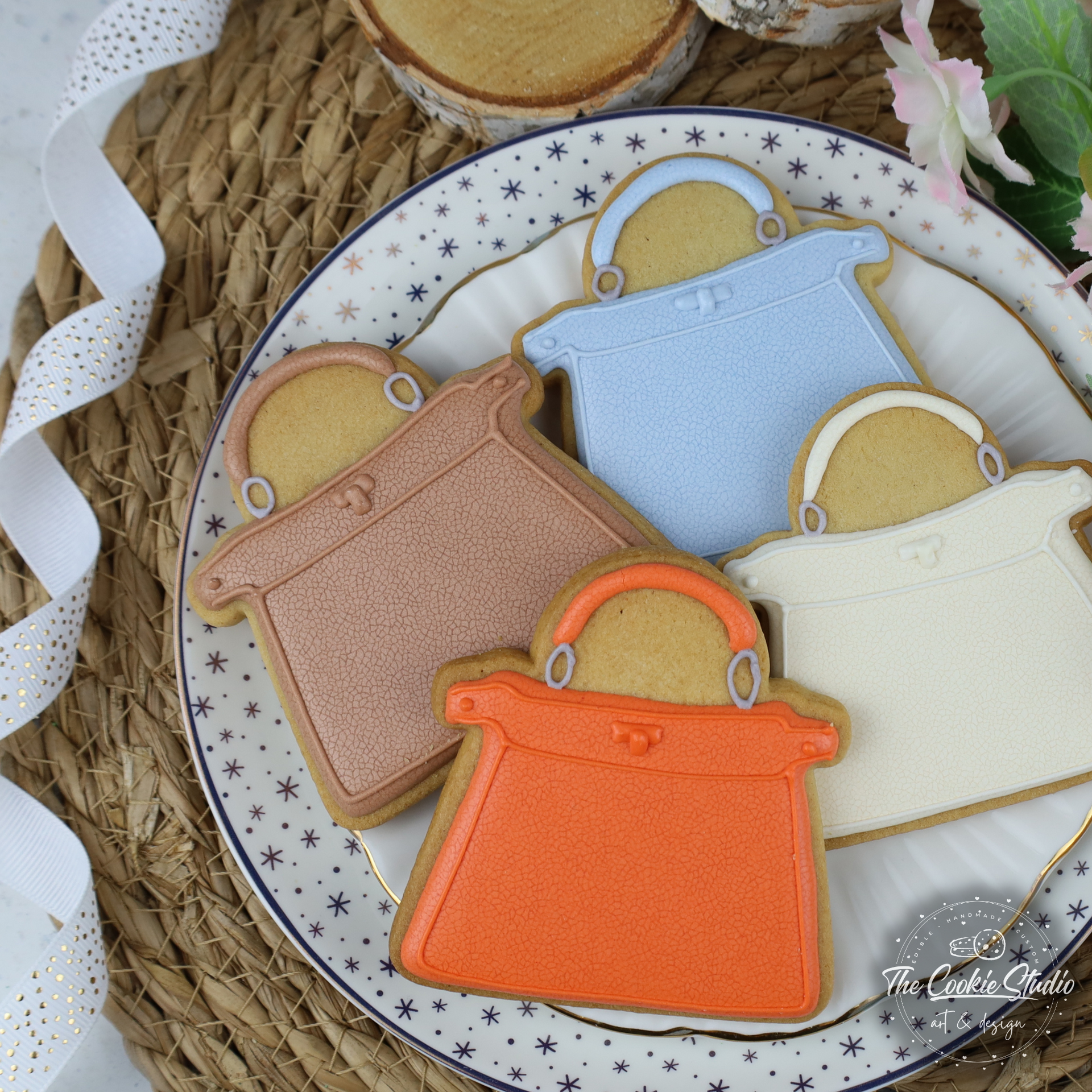 Koekjes in de vorm van handtassen in verschillende kleuren, uitgestald op een bord.