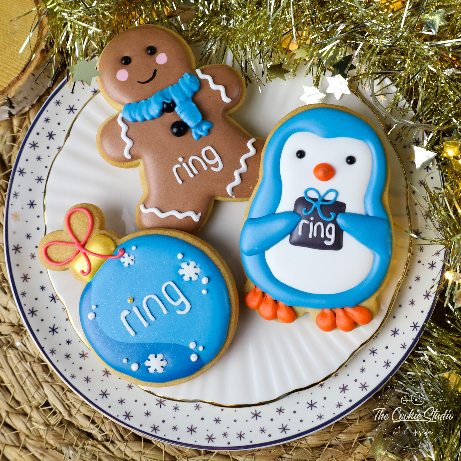 Kerstkoekjes: een peperkoekmannetje, een pinguïn en een kerstbal, allemaal met het merk