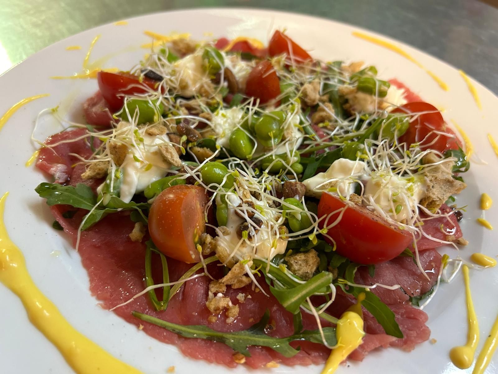 Un piatto bianco con sopra un'insalata di carne e verdure.