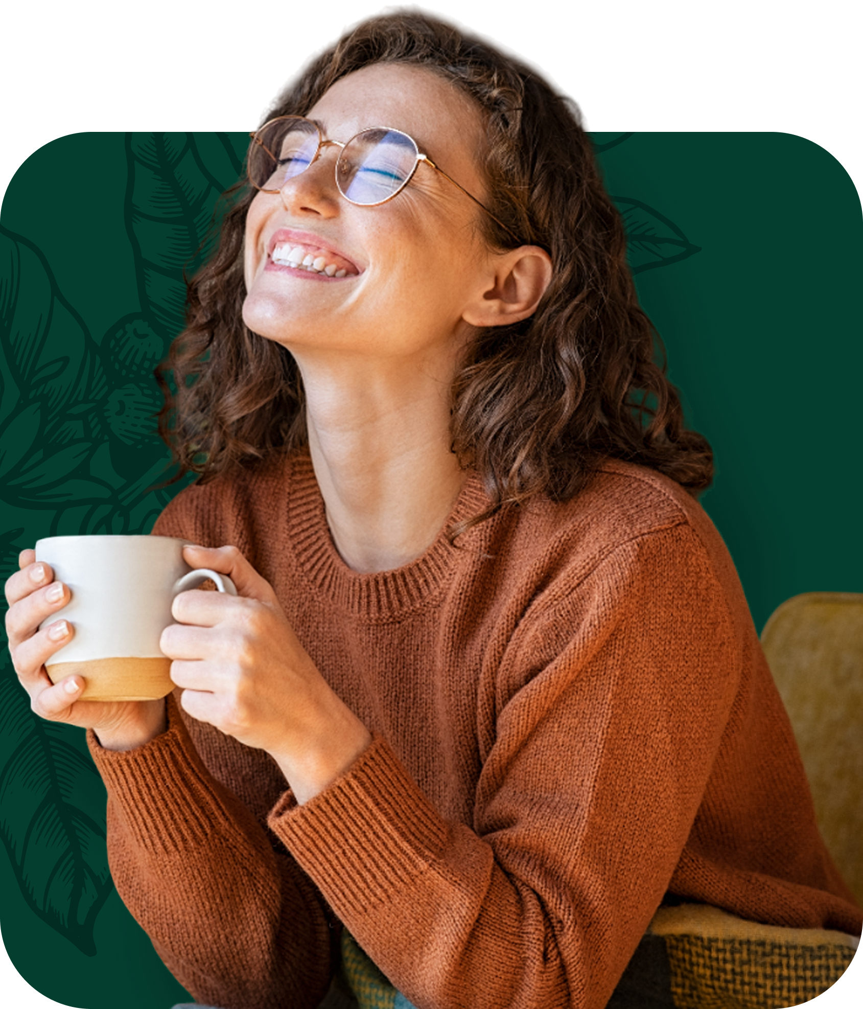 Woman smiling, holding a mug, wearing glasses and a brown sweater, in a room with green accents.