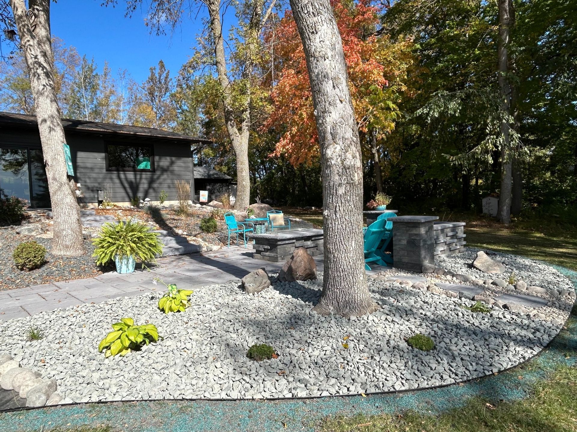 Backyard with a deck, pool, and path being built. Dark soil, gray bricks, green grass.