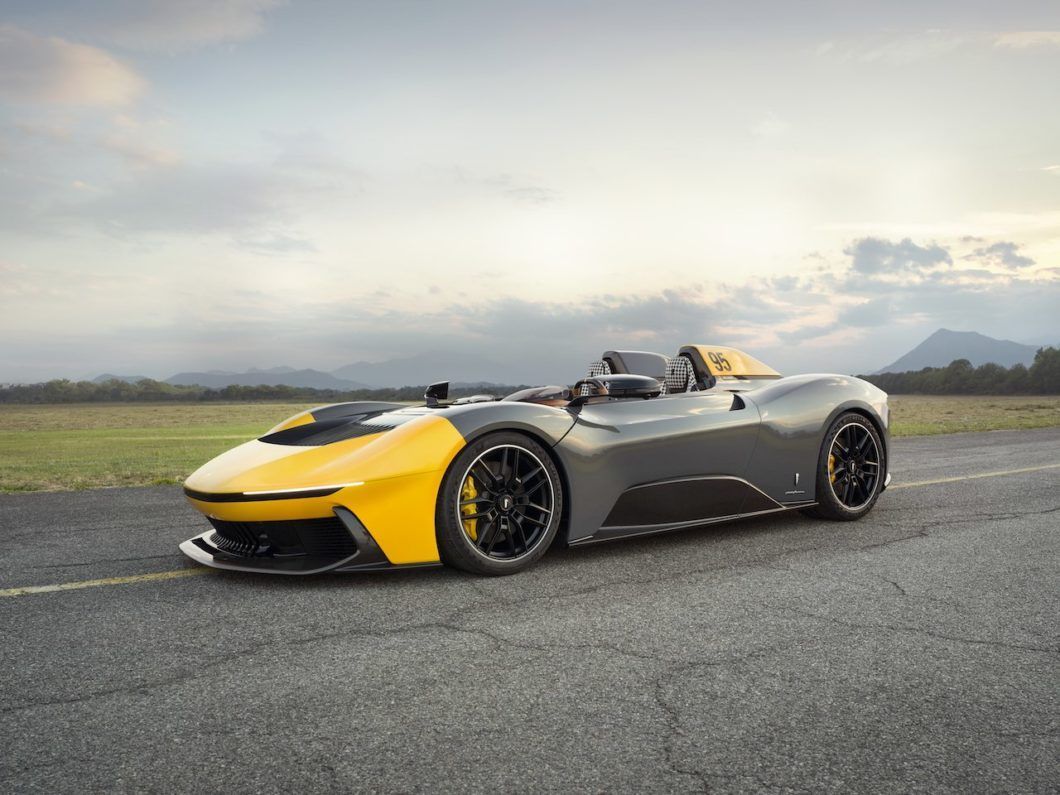 A yellow and gray sports car is parked on the side of a road.