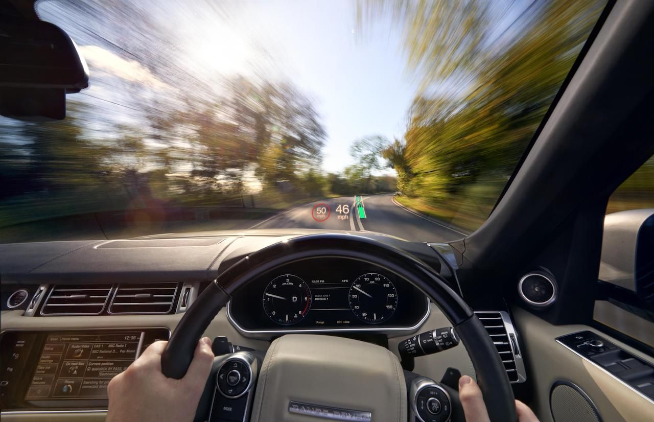 A person is driving a range rover on a country road.