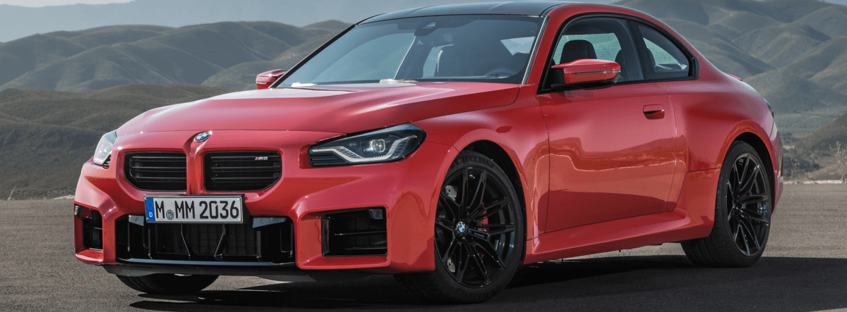 A red bmw m3 is parked on the side of the road.