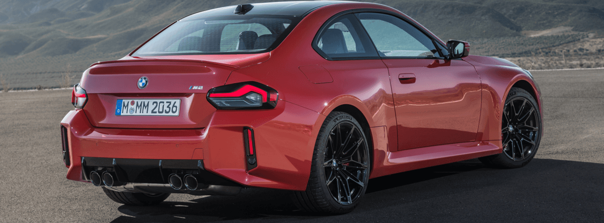 A red bmw m2 is parked on the side of the road.