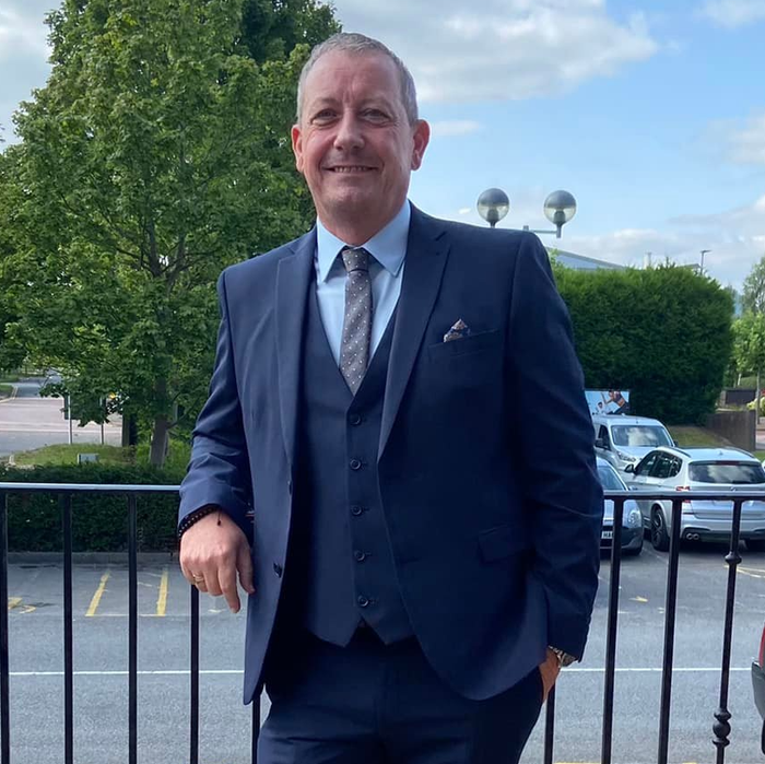 A man in a suit and tie is leaning against a railing
