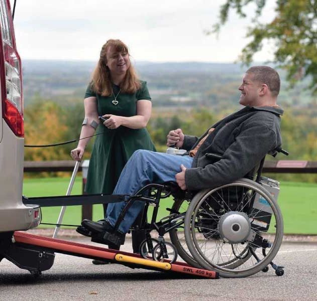 A man in a wheelchair is being towed by a van