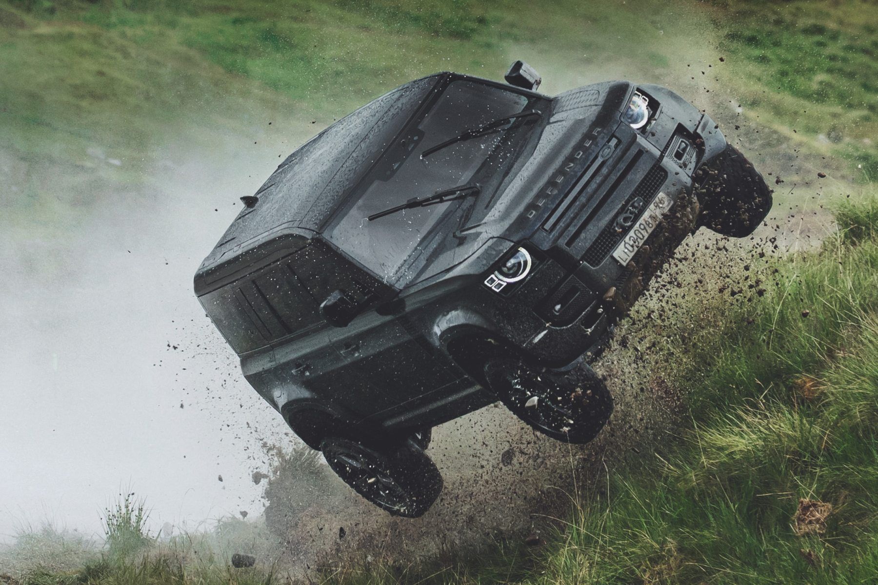 A black car is flying through the air in a field.