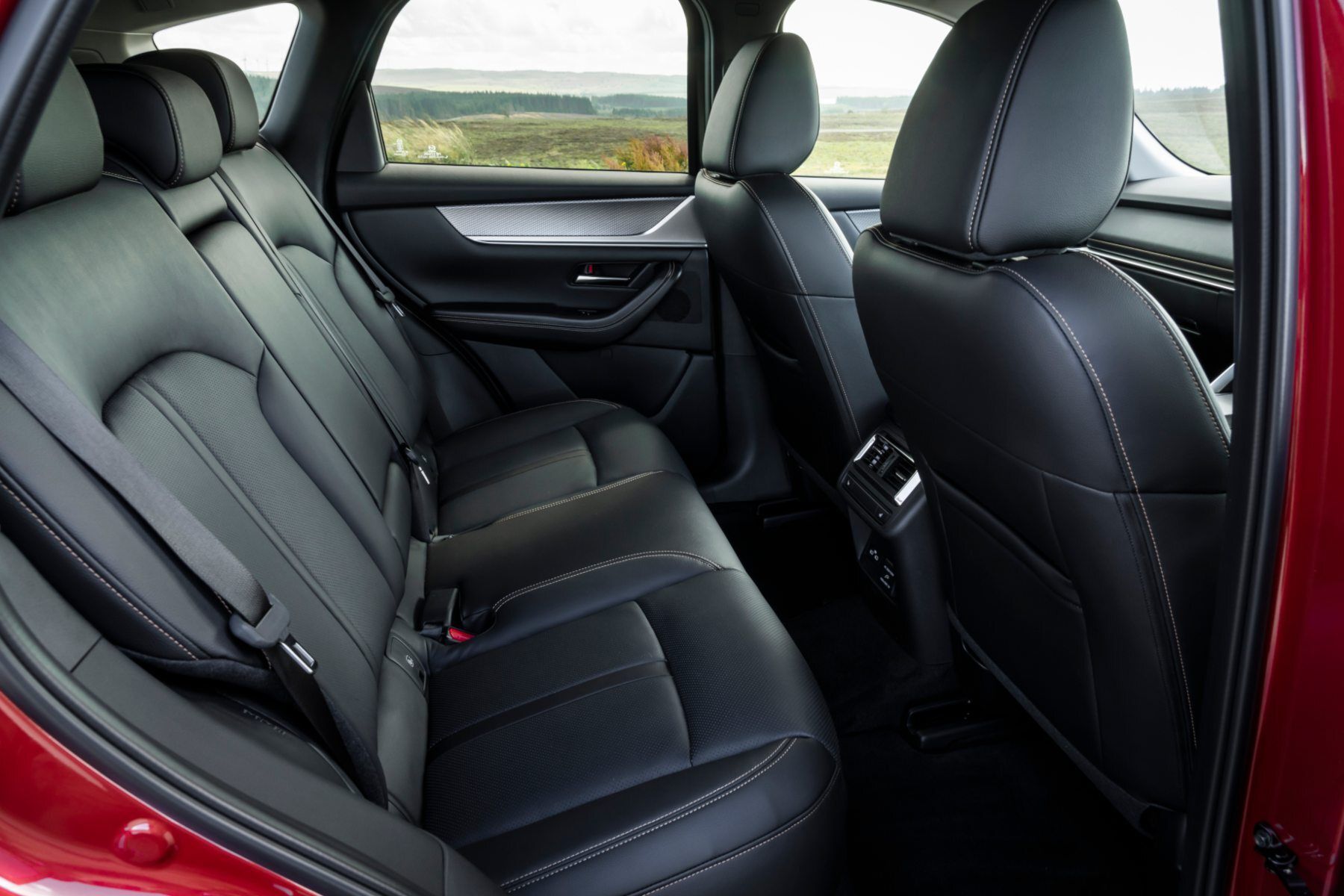 The back seat of a red car with black leather seats