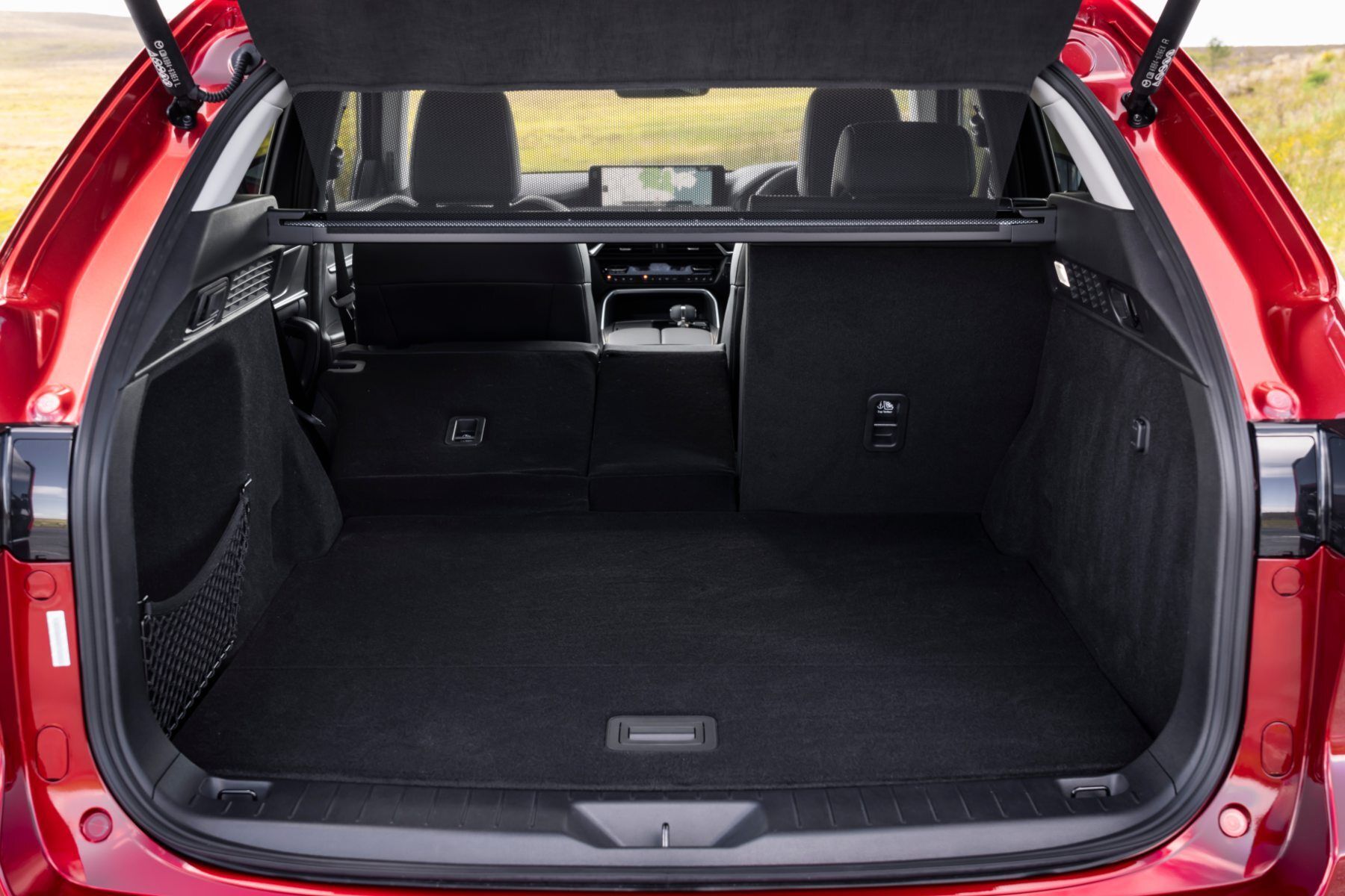 The trunk of a red car is open and empty.