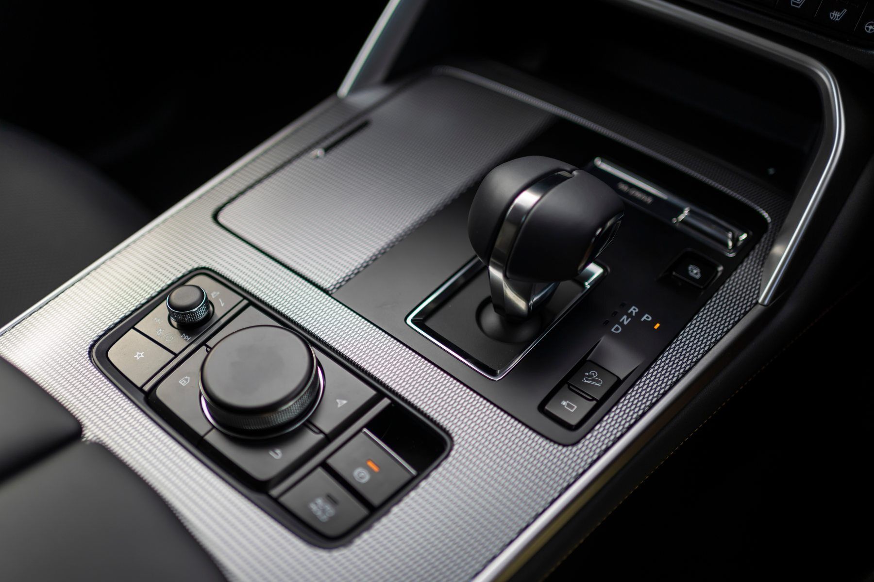 A close up of a car 's dashboard with a shifter and buttons.