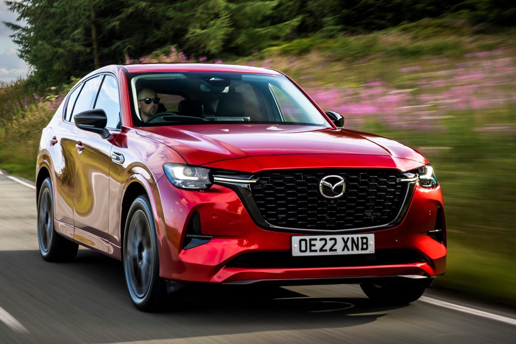 A red mazda cx-30 is driving down a road.