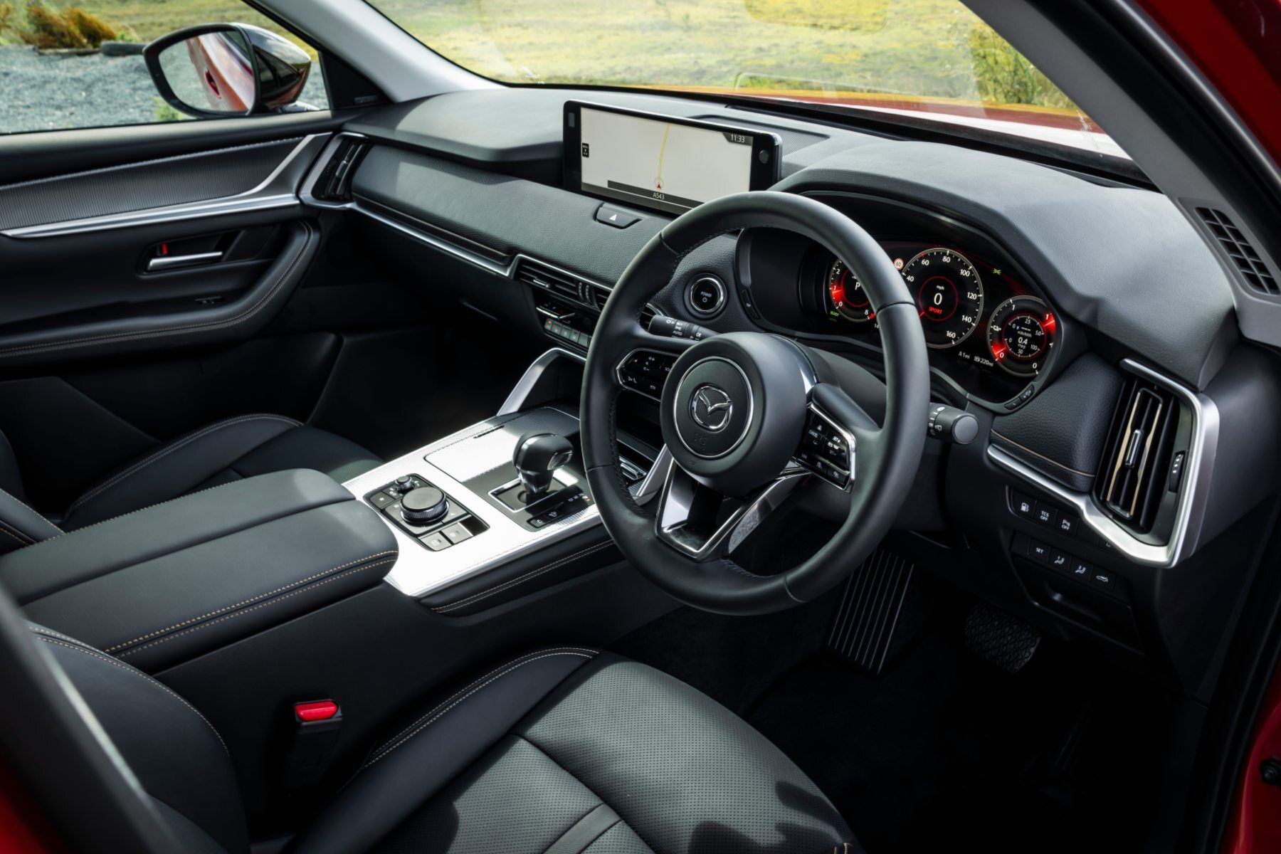 The interior of a red car with a steering wheel and dashboard.